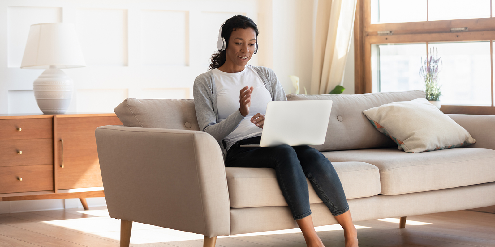 Woman with headphones sitting at computer on couch